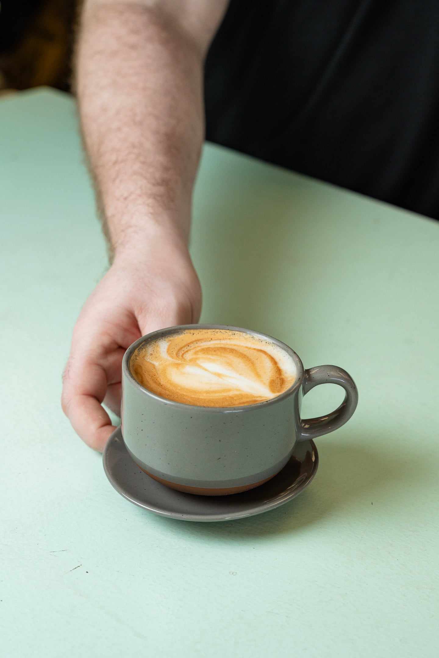 A latte with heart latte art held in two hands
